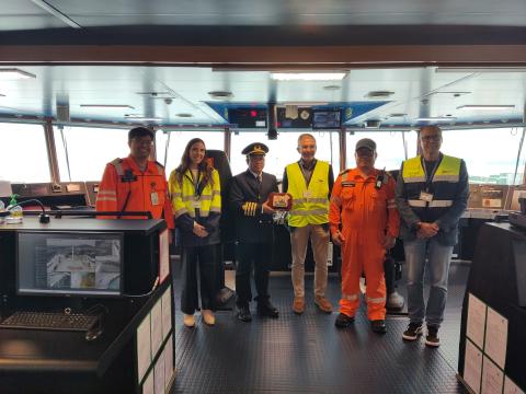 César Díaz (tercero por la derecha) entrega la metopa al capitán del barco (cuarto por la derecha), Edgar Paul P. Buhia, acompañado por personal del barco y por Elisabet Fuentes, del servicio comercial de la APS. Primero por la derecha, Manuel Trueba, director RoRo de Davila Agencias y Servicios Portuarios.